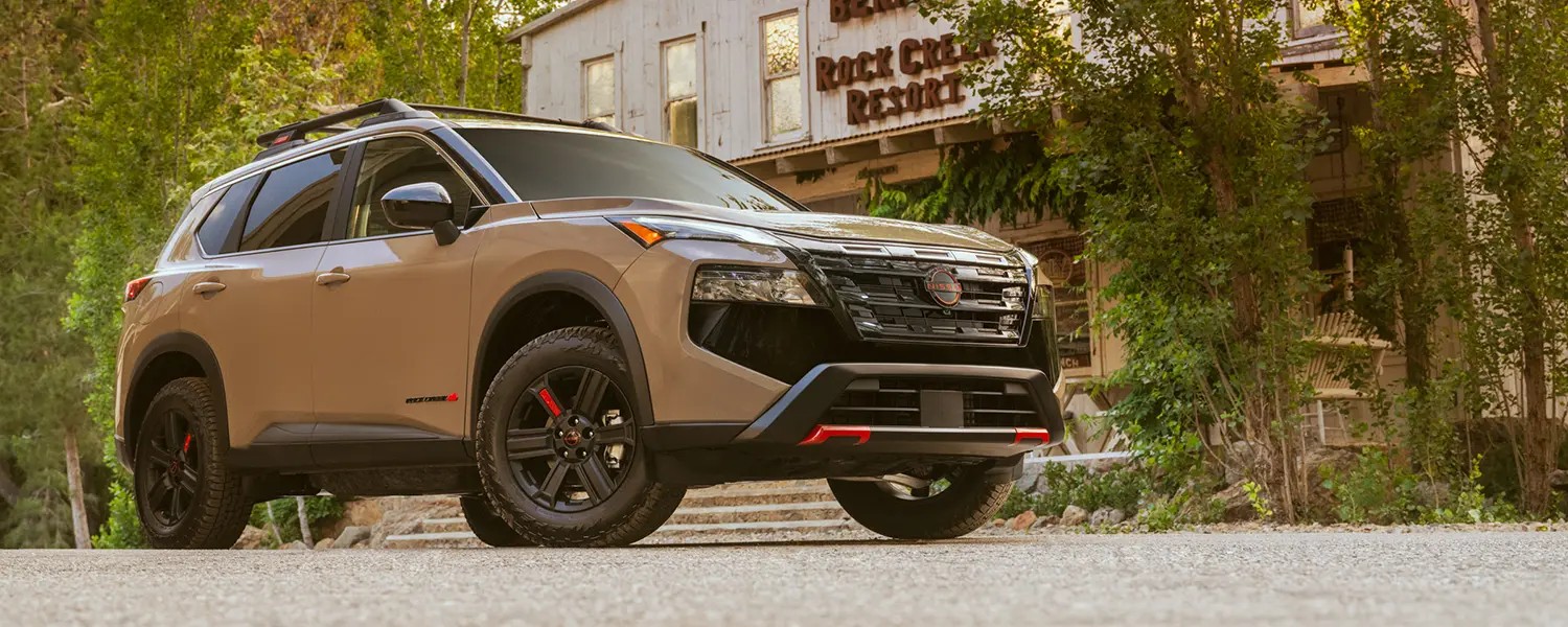 Tan Nissan Rogue parked beside a leafy streetscape.