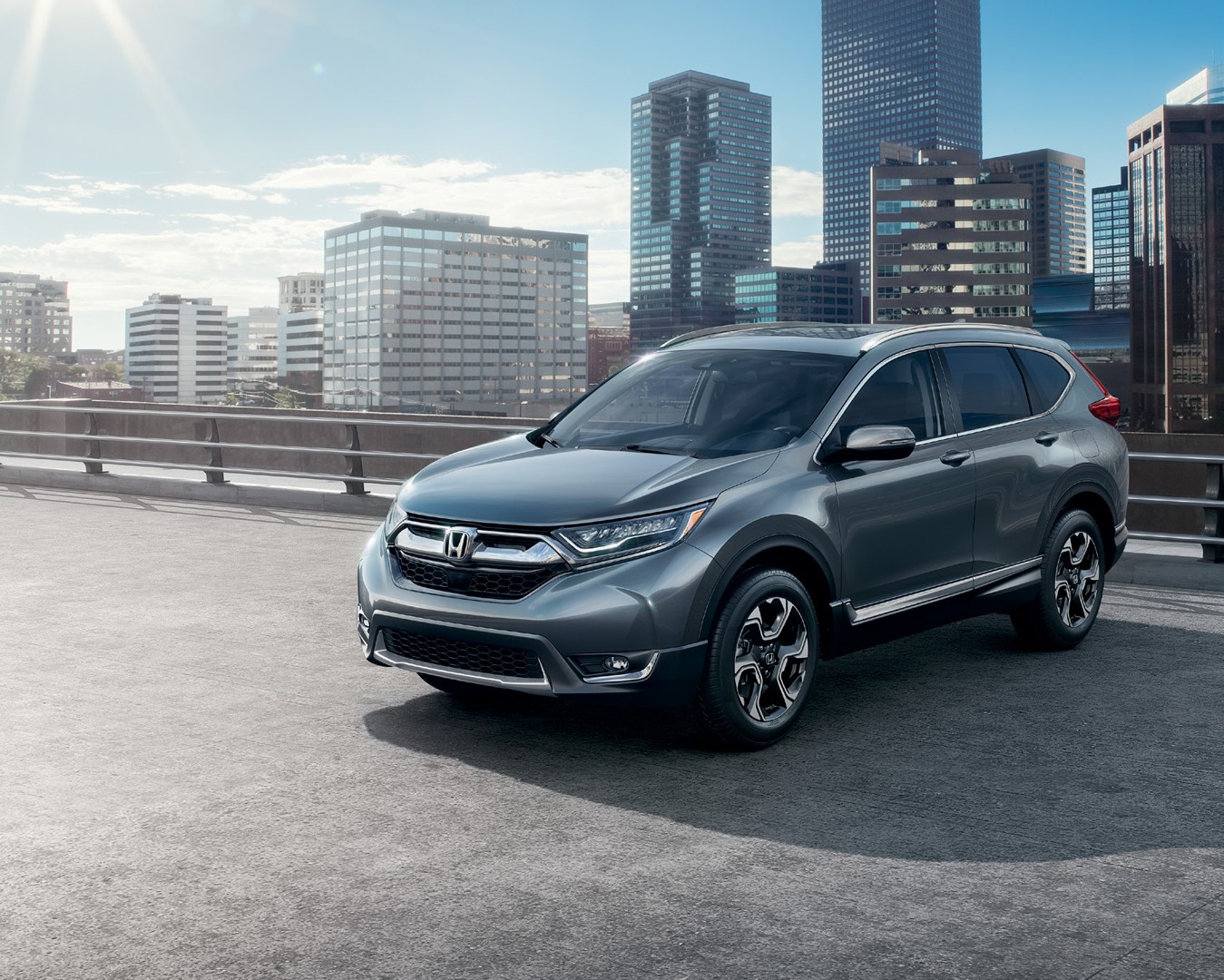 Gray Honda CR-V parked with a city skyline behind it.